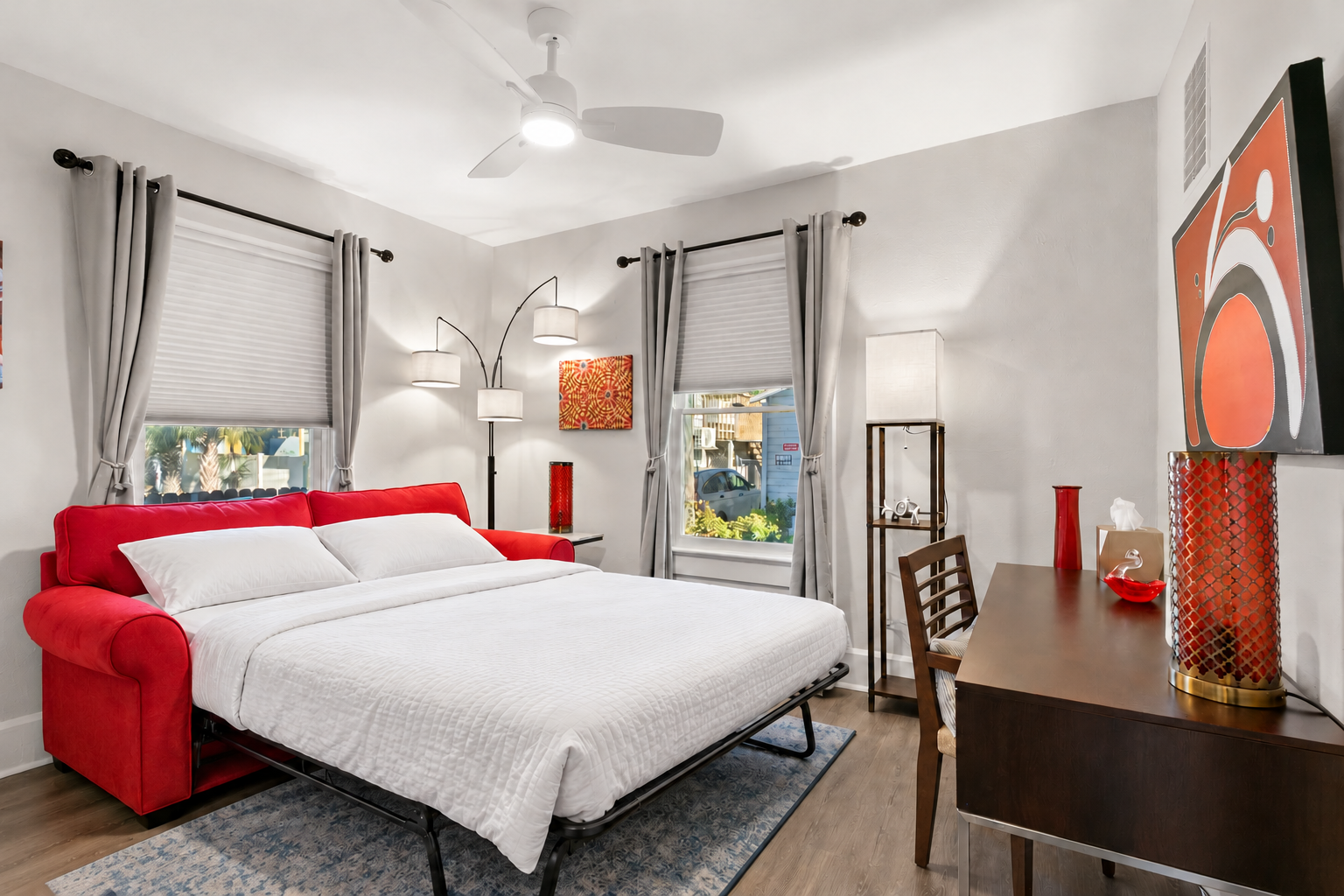AI-generated illustration of the red sofa opened as a bed with white bedding, coffee table removed and office desk retained